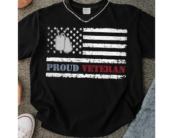 May include: Black t-shirt featuring a distressed American flag design with dog tags and the words "PROUD VETERAN" in white, red, and blue. The shirt has a crew neck and a relaxed fit, suitable for casual wear.