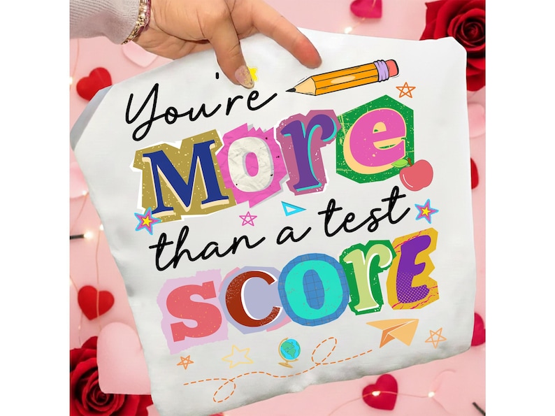 May include: White pillowcase with the text "You're More than a test SCORE" in colorful, block letters. A yellow pencil and various small illustrations, including stars and an apple, are also featured.