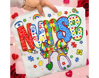 May include: White t-shirt with the word "NURSE" in colorful, patterned letters. The design includes a rainbow, puzzle pieces, a stethoscope, and a syringe. The shirt is held up by a hand.
