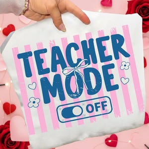 Puede incluir: Funda de almohada blanca con rayas verticales rosas y las palabras "TEACHER MODE OFF" en azul. El diseño incluye una zapatilla de ballet, corazones y flores. La funda de almohada está sujeta por una mano.
