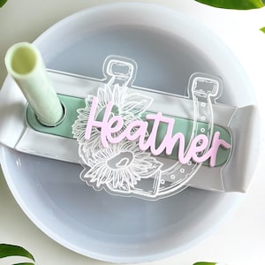 May include: A white diffuser with a clear water reservoir and a green tube. The diffuser has a white sticker with a horseshoe design and the name "Heather" written in pink.