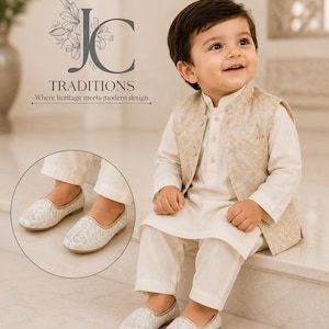 May include: A cream-colored kurta pajama set paired with a beige patterned vest and matching slip-on shoes. The text JC TRADITIONS Where heritage meets modern design is visible. The outfit features a long-sleeved tunic, trousers, and a waistcoat.