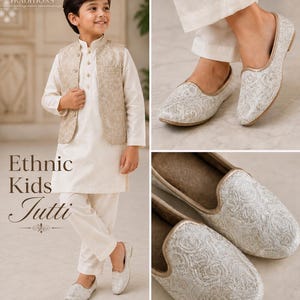 May include: A young boy in a cream-colored ethnic outfit, including a vest, kurta, and pants, is wearing matching embroidered Jutti shoes. The shoes and vest feature intricate patterns. The image also displays the text "Ethnic Kids Jutti".