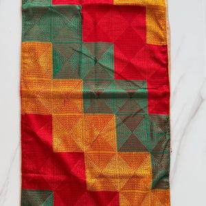 May include: A rectangular textile runner featuring a geometric grid pattern composed of alternating squares in vibrant red, golden yellow, and deep green. Each square contains intricate, fine-stitched diagonal lines forming a subtle pyramid texture.