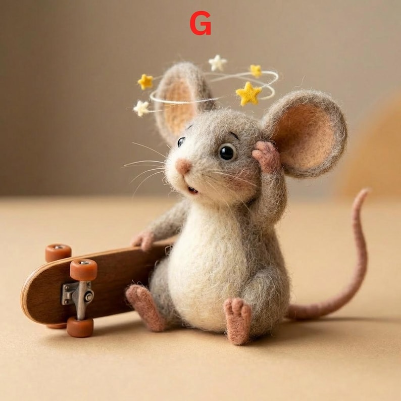 May include: A felt mouse figurine with a surprised expression, holding a miniature skateboard. The mouse has large ears, a long tail, and a star-shaped design above its head. The letter "G" is in the top left corner.
