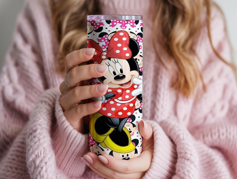 K&ouml;nnte beinhalten: Ein Edelstahlbecher mit einem farbenfrohen Minnie Mouse-Design. Der Becher zeigt Minnie in ihrem klassischen roten Polka-Dot-Kleid und ihrer Schleife. Der Hintergrund ist wei&szlig; mit rosa Punkten und Minnie Mouse-Silhouetten.