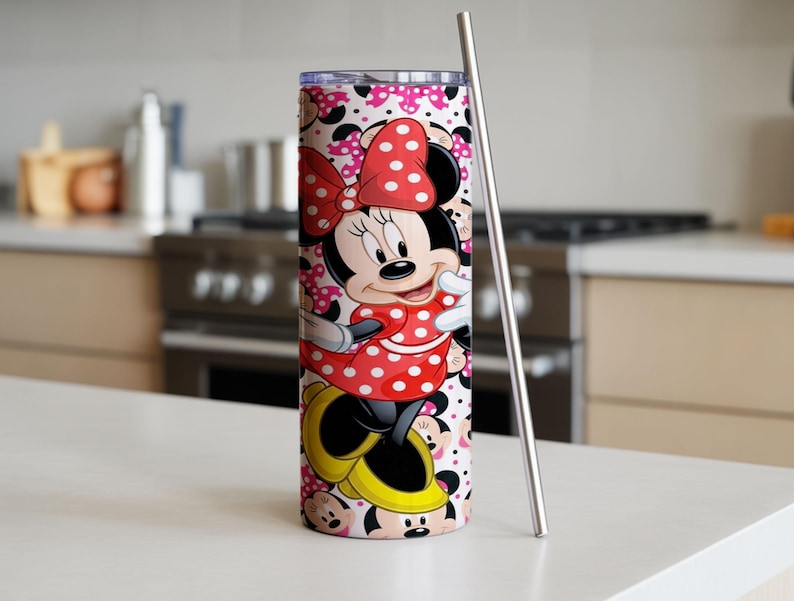 K&ouml;nnte beinhalten: Ein Edelstahlbecher mit Minnie Mouse-Design. Der Becher hat ein rot-wei&szlig;es Polka-Dot-Muster, einen Edelstahlstrohhalm und einen Hintergrund aus Minnie Mouse-Gesichtern und rosa Schleifen. H&ouml;he ca. 25 cm.