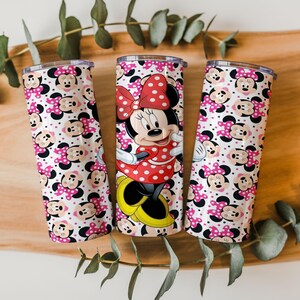 K&ouml;nnte beinhalten: Drei Edelstahlbecher mit Minnie-Maus-Motiv. Ein Becher zeigt ein vollst&auml;ndiges Minnie-Maus-Bild, w&auml;hrend die anderen beiden ein sich wiederholendes Muster von Minnie's Gesicht und rosa Schleifen mit Punkten haben. Die Becher sind zylindrisch.