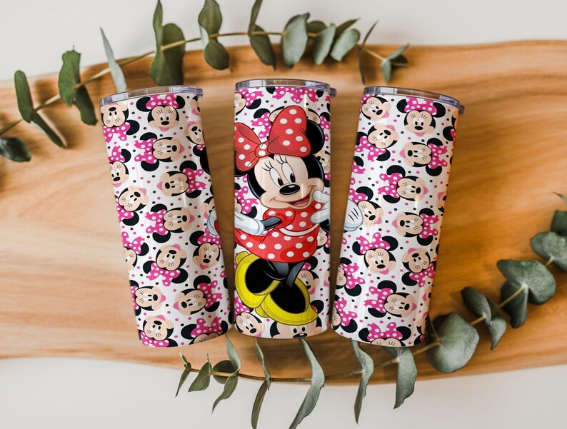 K&ouml;nnte beinhalten: Drei Edelstahlbecher mit Minnie-Maus-Motiv. Ein Becher zeigt ein vollst&auml;ndiges Minnie-Maus-Bild, w&auml;hrend die anderen beiden ein sich wiederholendes Muster von Minnie's Gesicht und rosa Schleifen mit Punkten haben. Die Becher sind zylindrisch.