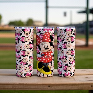 K&ouml;nnte beinhalten: Drei Edelstahlbecher mit Deckel. Ein Becher zeigt Minnie Mouse in einem roten gepunkteten Kleid und einer Schleife. Die anderen beiden Becher haben ein Muster aus Minnie Mouse-Gesichtern und rosa Punkten auf wei&szlig;em Hintergrund.