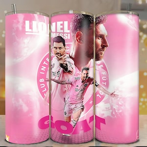 May include: A pink tumbler featuring images of Lionel Messi, with the word "GOAT" in large letters. The design includes the text "Lionel Messi" and "Club Internacional de Fútbol Miami". The tumbler has a silver straw.