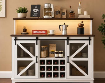 May include: A white wooden sideboard with a dark brown top, featuring two sliding barn-style doors with glass panels, a central open shelf, and a built-in wine rack. The unit includes interior lighting and black metal hardware accents.