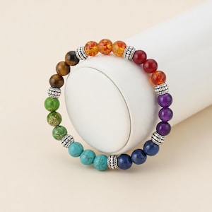 Puede incluir: Una pulsera de cuentas coloridas con un espectro de colores, incluyendo rojo, naranja, amarillo, verde, azul y morado. La pulsera está hecha con cuentas redondas y pulidas y espaciadores plateados. Esta pieza está diseñada para ser usada como accesorio de moda.