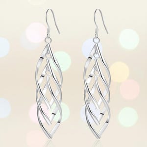 May include: A pair of silver-coloured drop earrings. Each earring has a series of intertwined, elongated, teardrop-shaped loops. The earrings have a hook closure and are designed to hang from the ear.