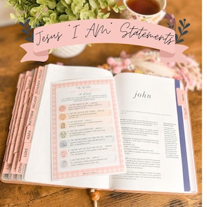 May include: An open Bible with pink tabbed pages and a printed card titled The Seven I Am Statements of Jesus resting on the open pages. The card features seven numbered points with icons and text detailing the statements from the Gospel of John.