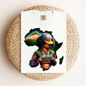 Könnte beinhalten: Weißes T-Shirt mit einer farbenfrohen Illustration einer Person, die eine Kappe und eine Jacke zum Thema Juneteenth trägt, vor dem Umriss des afrikanischen Kontinents. Das Design enthält leuchtende Farben und das Wort "Juneteenth".