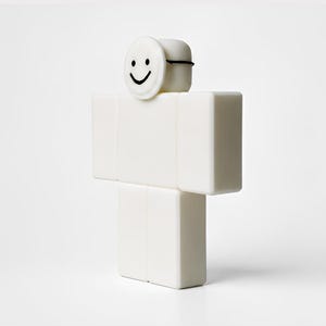 Puede incluir: Una figura blanca en forma de bloque con una cara sonriente en la parte superior. La figura es de color blanco s&oacute;lido, con una l&iacute;nea negra alrededor de la parte superior de la cabeza. La cara es un c&iacute;rculo blanco con una cara sonriente negra.