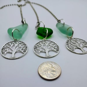 May include: Three necklaces featuring silver tree of life pendants and green sea glass beads. A UK coin is included for size reference. The necklaces are on a silver chain.