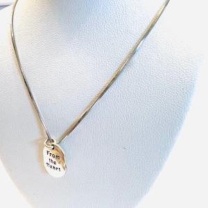 May include: A silver-toned necklace with a delicate chain and a small, oval pendant. The pendant is engraved with the words "From the heart" in a simple, elegant font. The necklace is displayed on a white mannequin.