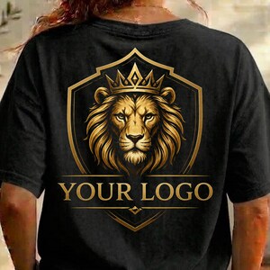 May include: Black t-shirt featuring a gold lion crest design. The crest includes a lion's head wearing a crown, set within a shield shape. The text "YOUR LOGO" is displayed below the lion image.