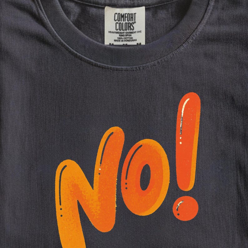 May include: Dark gray t-shirt with the word "No!" in orange, outlined in black. The exclamation point is a tall, vertical shape. The shirt has a crew neck and a tag that reads "Comfort Colors."