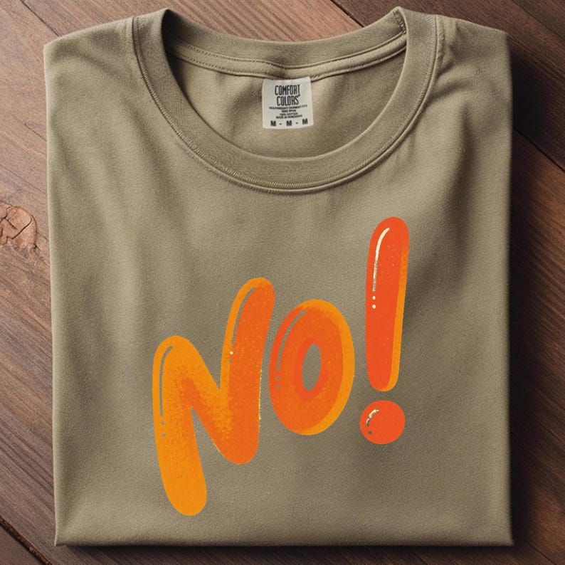 May include: A folded, olive-green t-shirt with the word "NO!" in large, orange, bubble letters. The exclamation point is also orange. The shirt has a tag that reads "Comfort Colors".