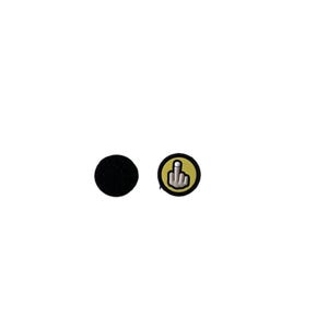 Peut inclure: Deux écussons sur fond blanc. L'un est un cercle noir, l'autre est un écusson circulaire avec un bord jaune et une main blanche faisant un doigt d'honneur.