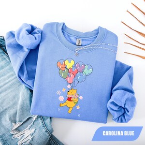 May include: A set of three ceramic mugs with a speckled, cream-colored glaze. Each mug features a different hand-painted design: a blue and green leaf, a yellow flower, and a red berry. The mugs have a simple, modern design.