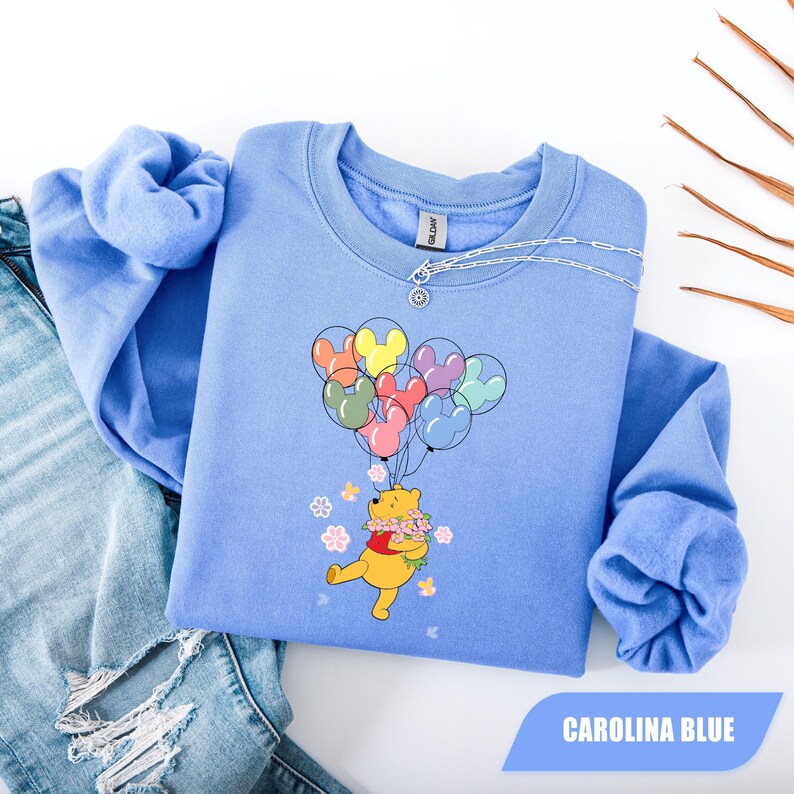 May include: A set of three ceramic mugs with a speckled, cream-colored glaze. Each mug features a different hand-painted design: a blue and green leaf, a yellow flower, and a red berry. The mugs have a simple, modern design.