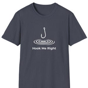 May include: Dark blue t-shirt with a white graphic of a fishing hook above concentric circles, with the text "Hook Me Right" below. The shirt has a crew neck and short sleeves.
