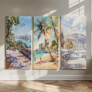 May include: A triptych of watercolor paintings depicting cityscapes. The paintings feature scenes of Belgrade, Darwin, and Hobart, each with the city's name and country printed at the bottom. The artwork is displayed on a neutral wall.
