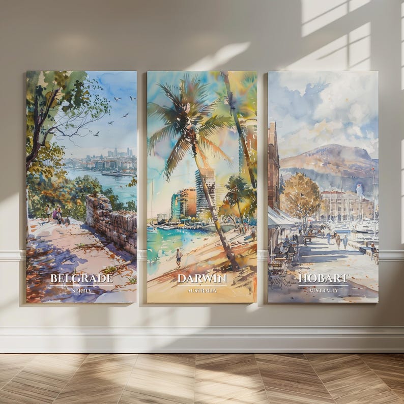 May include: A triptych of watercolor paintings depicting cityscapes. The paintings feature scenes of Belgrade, Darwin, and Hobart, each with the city's name and country printed at the bottom. The artwork is displayed on a neutral wall.
