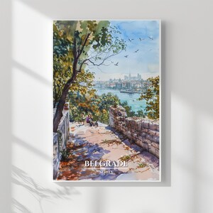 May include: Watercolor print of Belgrade, Serbia, featuring a scenic view of the city skyline, river, and trees. The artwork includes a stone wall and a path leading to a viewpoint. The print has a white border and the text "BELGRADE SERBIA".