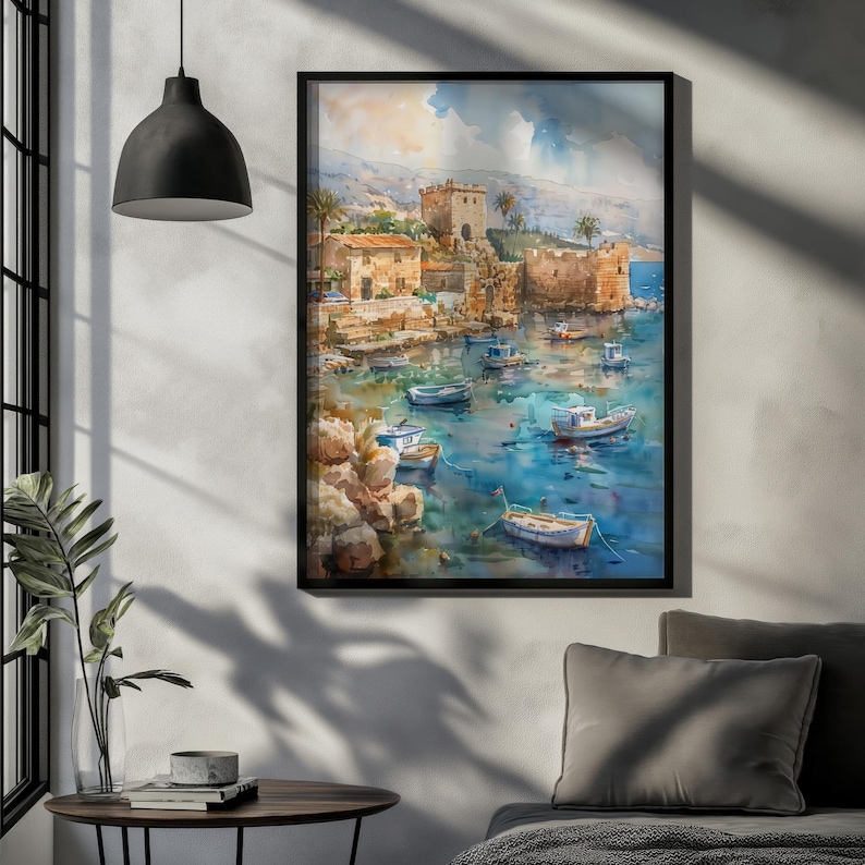 Könnte beinhalten: Aquarellmalerei einer Küstenlandschaft mit einer Steinfestung, Gebäuden und Booten im Wasser. Das Kunstwerk, in Blau-, Beige- und Brauntönen, ist in Schwarz gerahmt und hängt an einer weißen Wand. Das Gemälde hat einen mediterranen Stil.