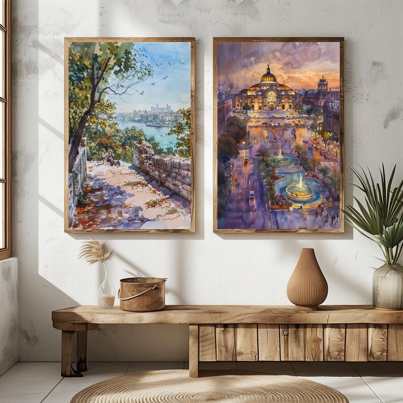 May include: Two framed watercolor paintings. One depicts a path overlooking a river and city, the other a city square with a domed building. Both are in wooden frames, displayed on a wooden bench.