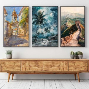 Puede incluir: Tres pinturas de acuarela enmarcadas que representan escenas arquitect&oacute;nicas y paisaj&iacute;sticas. Una muestra una calle europea, otra una escena tropical con palmeras y la tercera, una vista de la Gran Muralla China. Las pinturas est&aacute;n sobre un mueble de madera.