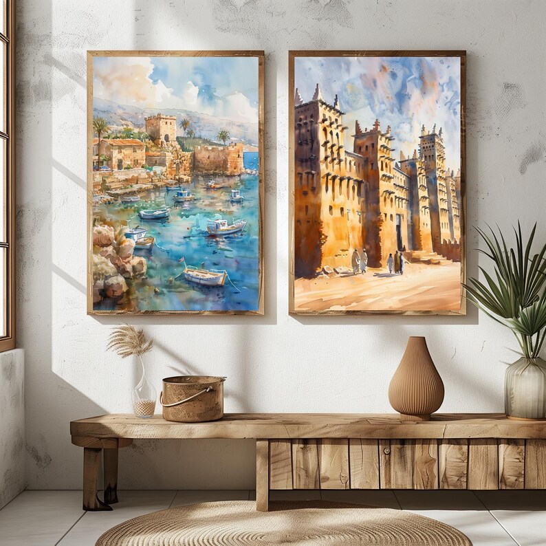May include: Two framed watercolor paintings depict coastal scenes. One shows a harbor with boats and buildings, the other features a city with tall, ornate structures. Both paintings have wooden frames and are displayed on a wooden bench.