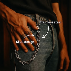 Op de afbeelding: Een roestvrijstalen portemonnee ketting met een schedel ontwerp. De ketting is bevestigd aan een spijkerbroek. De tekst "Stainless steel" en "Skull design" zijn zichtbaar.