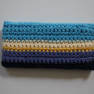 May include: A crocheted pouch with stripes of blue, cream, yellow, and purple yarn.