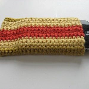 May include: A crocheted phone case with a striped pattern in shades of yellow, orange, and red. The case is designed to fit a smartphone.
