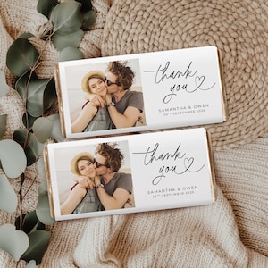 Può includere: Due confezioni di barrette di cioccolato con la foto di una coppia che si bacia. Le confezioni riportano la scritta "thank you" in corsivo con un cuore, e i nomi "SAMANTHA & OWEN" e la data "20th SEPTEMBER 2025".