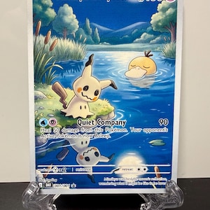 Könnte beinhalten: Eine Mimikyu & Psyduck Sammelkarte mit 130 KP. Die Illustration zeigt Mimikyu an einem grasbewachsenen Ufer und Enton in einem blauen Teich unter einem Vollmond. Der Text enthält Quiet Company, Angriffsdetails und einen Text über den Mond.