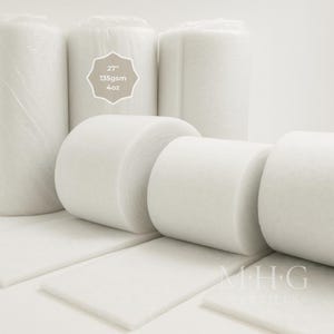 May include: White batting rolls and rectangular sheets are shown. The rolls are wrapped in clear plastic. A label indicates the batting is 68.58 cm wide, 135 gsm, and 113.4 grams. The MHG Textiles logo is visible.