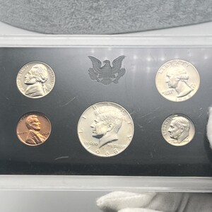 May include: A 1968 United States proof set, featuring a half dollar, quarter, dime, nickel, and penny. The coins are displayed in a protective case, showcasing their detailed designs and historical significance. The set includes the iconic Kennedy half dollar.