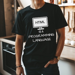 May include: Black t-shirt with a white graphic of a computer monitor displaying "HTML" and the text "IS A PROGRAMMING LANGUAGE" in a casual font. The shirt is short-sleeved and appears to be made of cotton or a similar fabric.