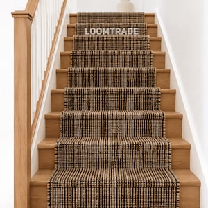 May include: A woven stair runner featuring a textured pattern of alternating dark brown and natural tan fibers. The runner is installed on wooden stairs and displays the white text LOOMTRADE on the second step from the top of the runner.