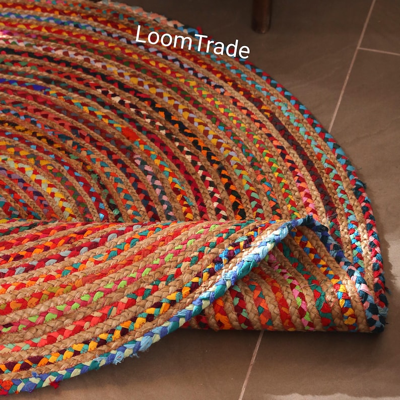May include: A circular jute rug with a braided design, showcasing a vibrant array of colours. The rug incorporates shades of red, orange, yellow, green, blue, and purple. The text "LoomTrade" is visible on the rug.chindi round rug, braided round rug, round jute rugs, cotton braided rug, custom size rug, cotton jute rug, eco friendly rugs, bohemian rug, boho decor rugs, circle jute rugs, cotton rug, floor mat rugs, rugs for living room