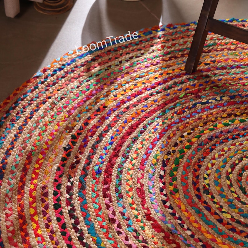 May include: A circular jute rug with a braided design, showcasing a vibrant array of colours. The rug's pattern includes concentric circles of red, orange, yellow, green, blue, and pink. The text "LoomTrade" is visible on the rug.chindi round rug, cotton braided rug, custom size rug, cotton jute rug, round area rug, traditional rug, bohemian rug, boho decor rug, cotton rug, entryway round rug, handmade rug, round indian cotton rug, rugs for living room
