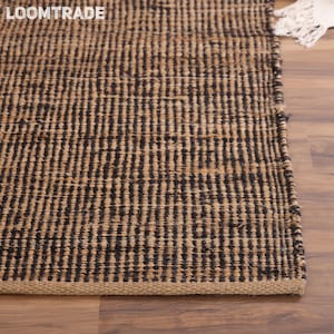 May include: A rectangular area rug featuring a woven pattern of alternating vertical stripes in dark brown and natural tan fibers. The rug has a thick, textured weave and a finished edge, with the text LOOMTRADE visible in the upper left corner.