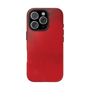 Pode incluir: Uma capa de smartphone vermelha com acabamento brilhante. A capa apresenta um sistema de câmera multi-lente no canto superior esquerdo e botões laterais pretos. A capa tem uma cor vermelha sólida com uma aparência sutil e texturizada.